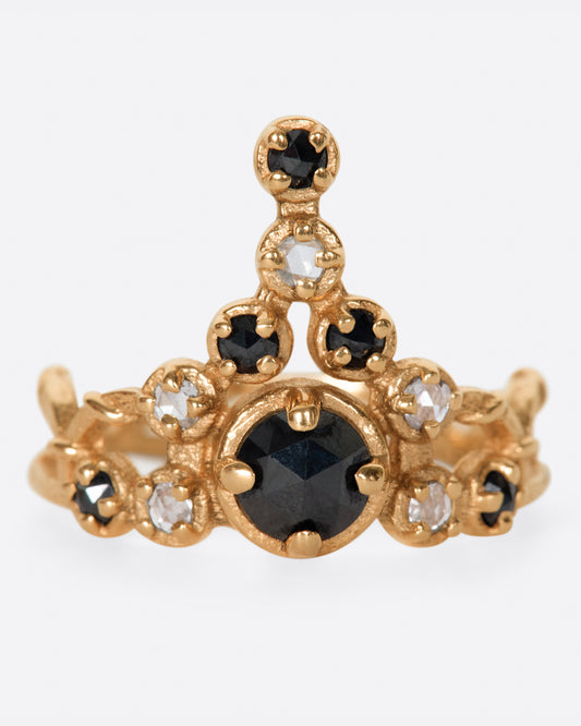 A yellow gold crown ring with a mix of black and white diamonds stacked into its peak. Shown from the front.