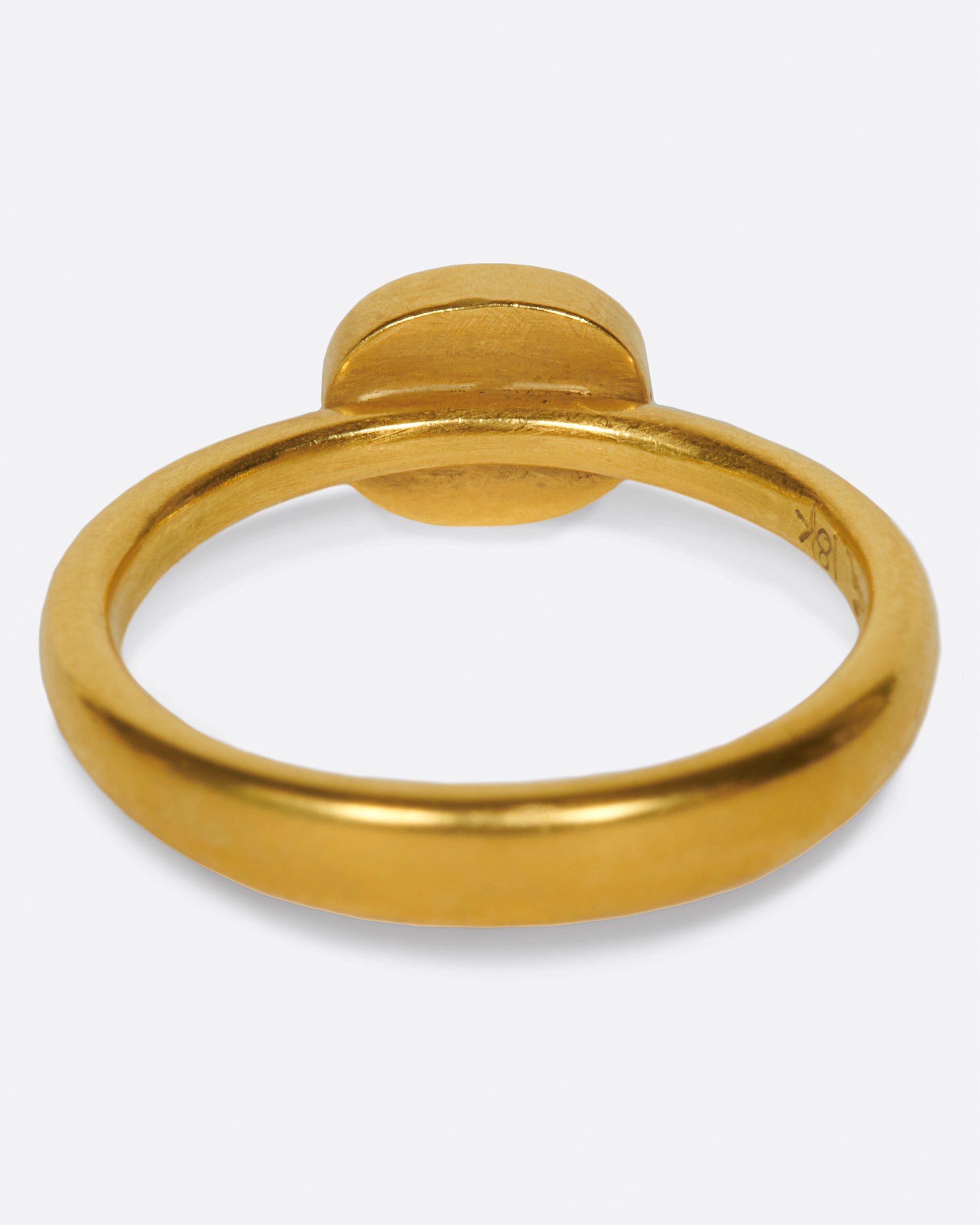 A pale grey, rose cut, oval diamond. Set horizontally on a simple, yellow gold band. Shown from the back.