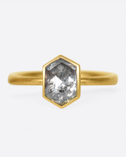 A yellow gold ring with a salt and pepper hexagonal diamond. Shown from the front.