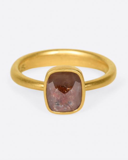 A yellow gold ring with a cushion shaped, rusty-red diamond. Shown from the front.