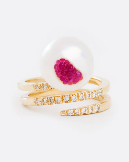 A yellow gold wrap ring with an organic freshwater pearl lined with rubies. Shown from the front.