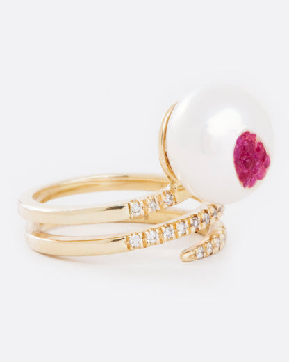 A yellow gold wrap ring with an organic freshwater pearl lined with rubies. Shown from the side.