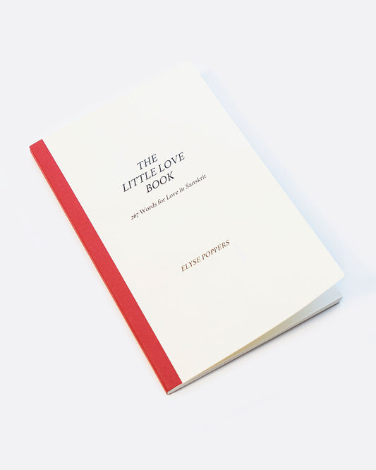 A white book with red binding. The cover reads: 'The Little Love Book 267 /Words for Love in Sanskrit ELYSE POPPERS'. Shown lying flat at an angle from the front.