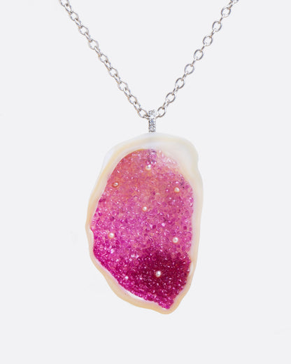 A large freshwater souffle pearl carved out and lined with ombre pink sapphires and seed pearls. It has a pave diamond lined bail and white gold cable chain. Shown from the front.