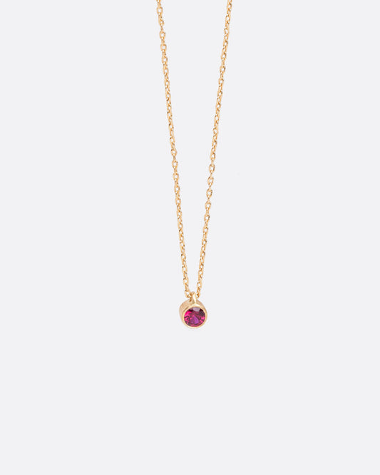 A yellow gold cable chain necklace with a round bezel set ruby pendant. Shown from the front.