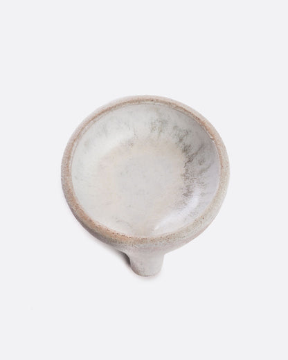 A black stoneware soap dish with a drainage spout. Shown from the top.