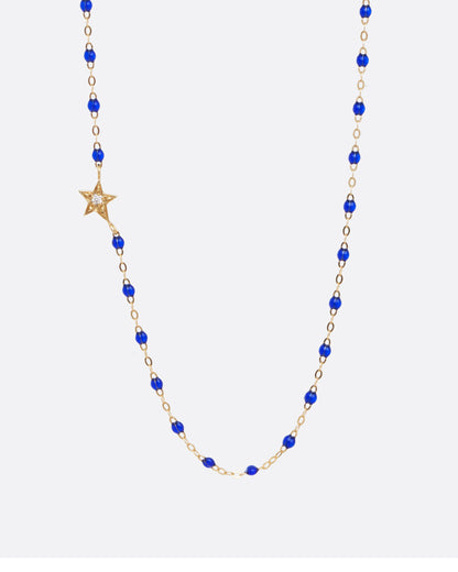 Yellow gold chain necklace with dark blue resin beads and off centered yellow gold star with diamond center