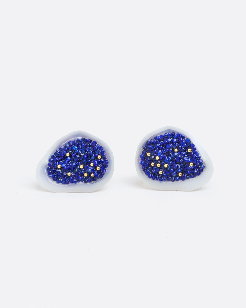 two earrings of a white souffle pearl that has been hollowed out and filled with small lapis pieces and small gold beads. with a yellow gold post back and yellow gold butterfly backing