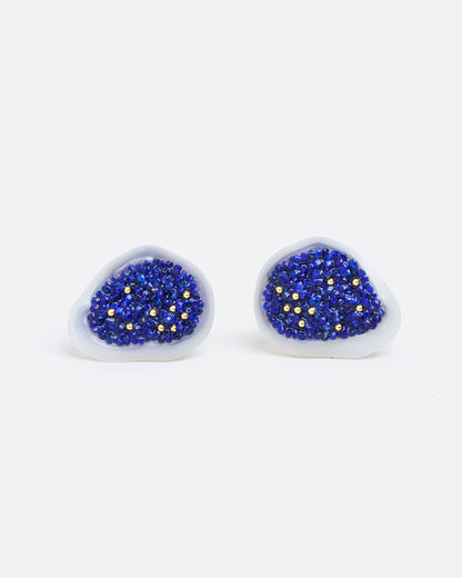 two earrings of a white souffle pearl that has been hollowed out and filled with small lapis pieces and small gold beads. with a yellow gold post back and yellow gold butterfly backing