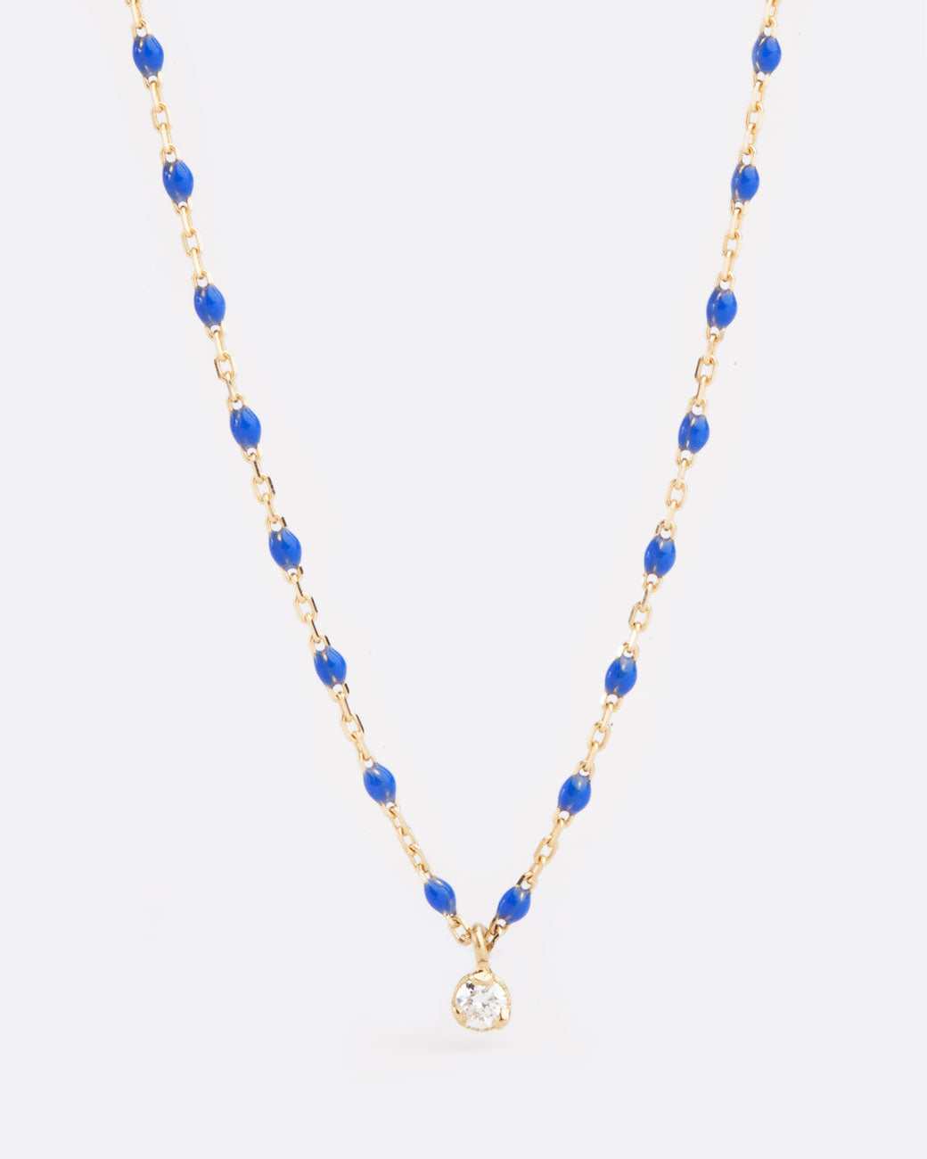 A yellow gold cable chain necklace with droplets of blue resin and a single diamond pendant. Shown from the front.