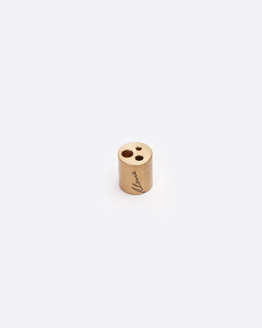 A brass incense stand showing three different size holes designed to accommodate different sizes of incense sticks. Shown from the front.