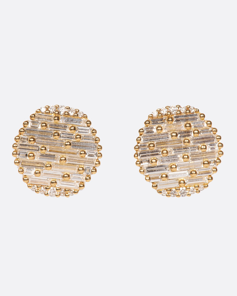 A pair of round yellow gold, slightly concave stud earrings covered in baguette diamonds. Shown from the front.