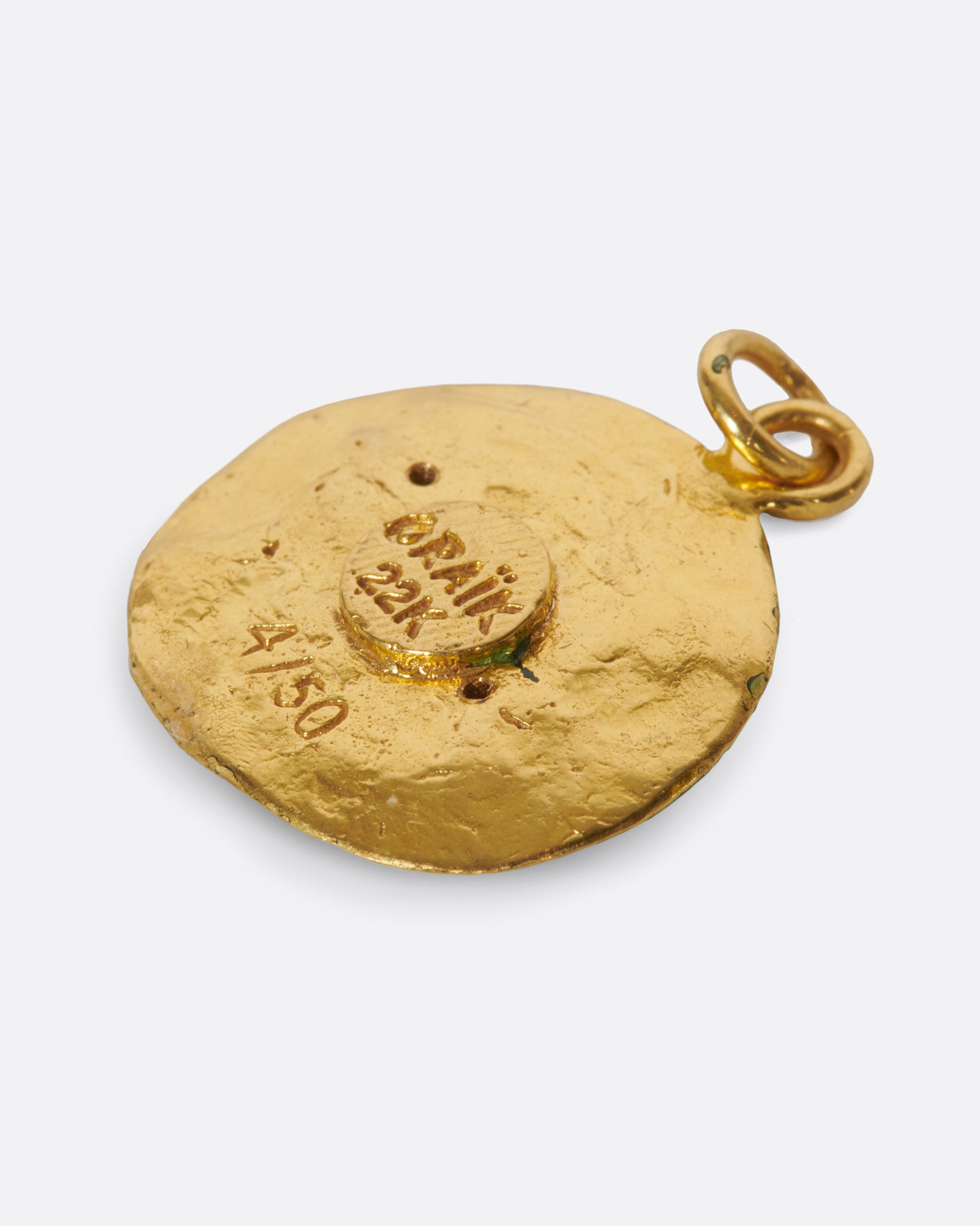A round hand-sculpted pendant with the Pisces symbol, each fish with a blue sapphire eye.