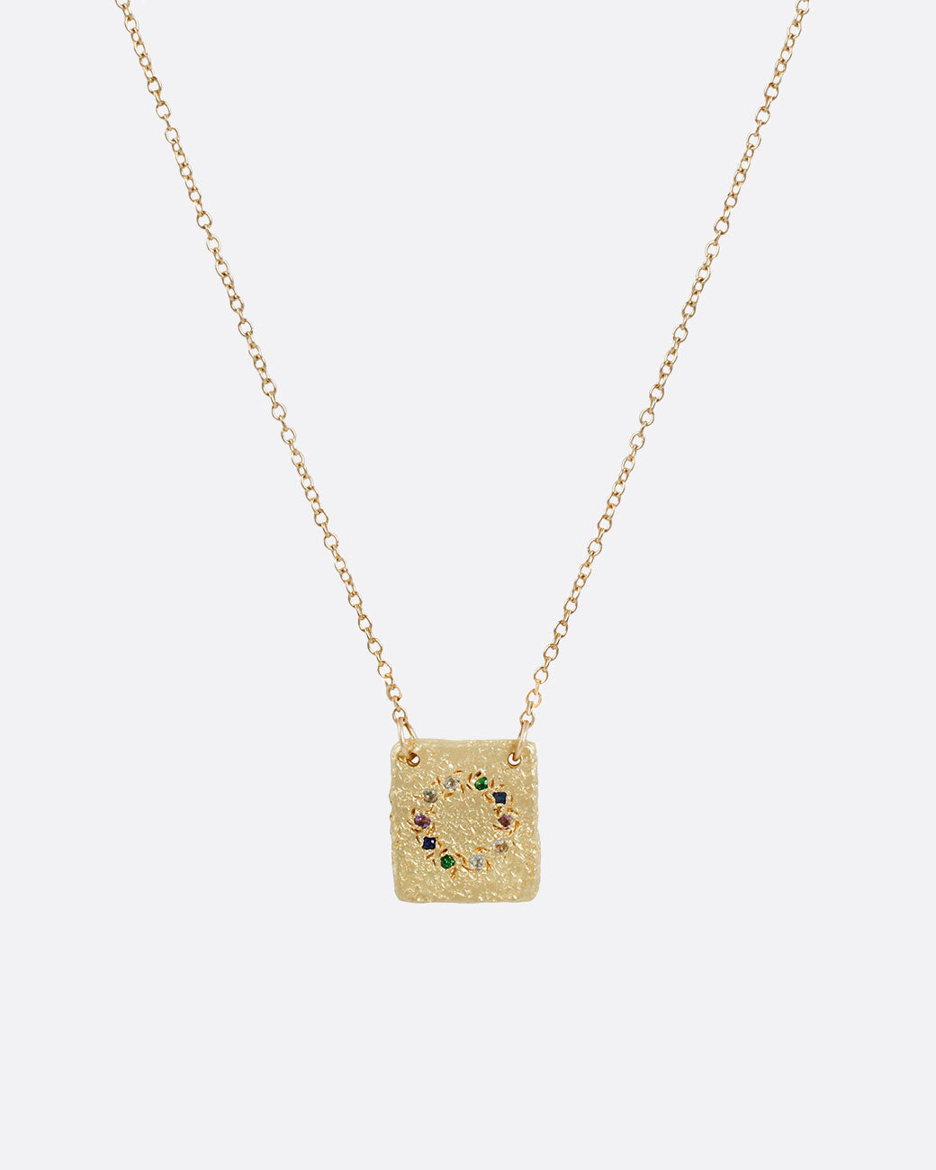 A textured 14k yellow gold square pendant with a circle of stones including amethyst, emerald, aquamarine and multicolor sapphires hanging on a cable chain. Shown from the front.