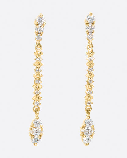 A pair of long yellow gold earrings with diamonds throughout. Shown from the front.