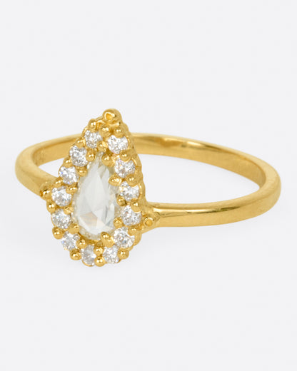 A yellow gold ring with a light champagne rose cut pear shaped diamond haloed by round diamonds. Shown from the side.