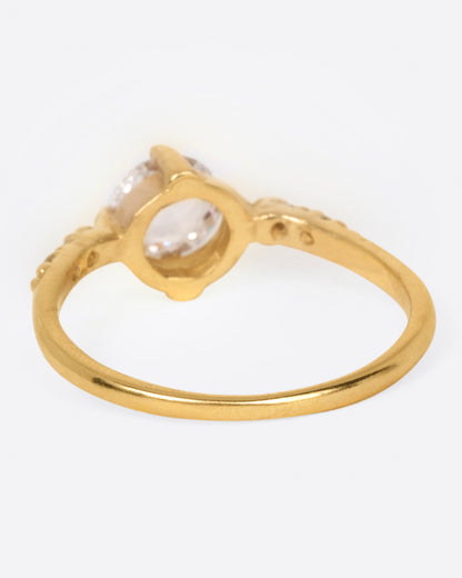 A yellow gold ring with a prong set rose cut diamond at the center and two diamonds on either side, shown from the back.