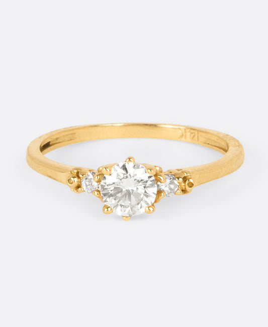 A yellow gold diamond ring with one large round central diamond and two smaller round diamonds on either side. Shown from the front.