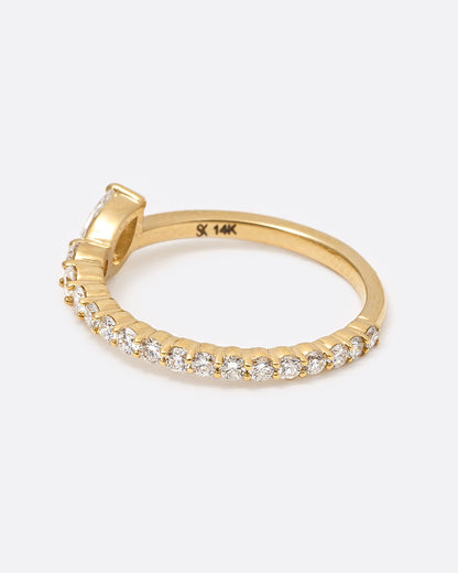 A yellow gold ring with graduated white diamonds halfway around and one pear shaped white diamond at its center, shown from the side.