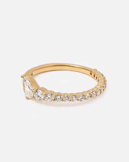1A yellow gold ring with graduated white diamonds halfway around and one pear shaped white diamond at its center shown from the side.