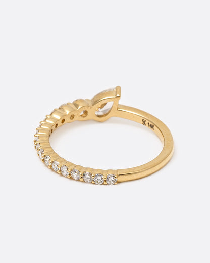 A yellow gold ring with graduated white diamonds halfway around and one pear shaped white diamond at its center, shown from the back.