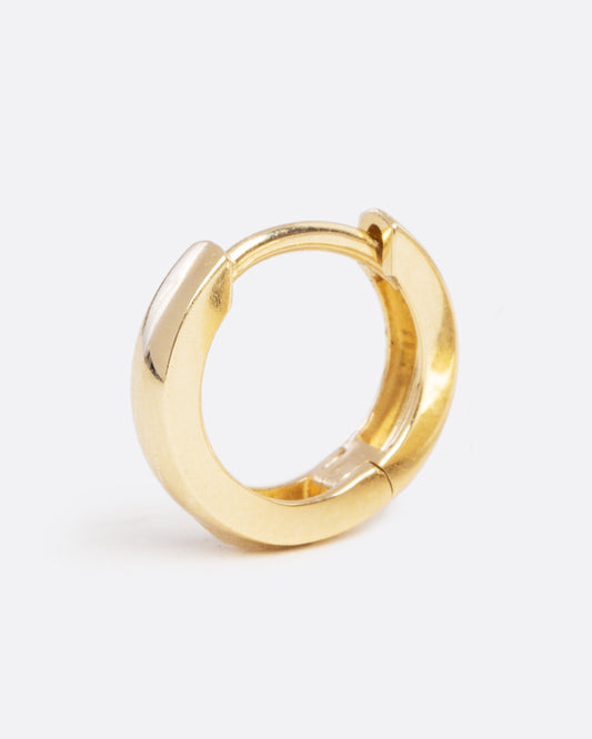 A yellow gold hoop earring with a hinge in the middle. Shown closed standing up from the side.