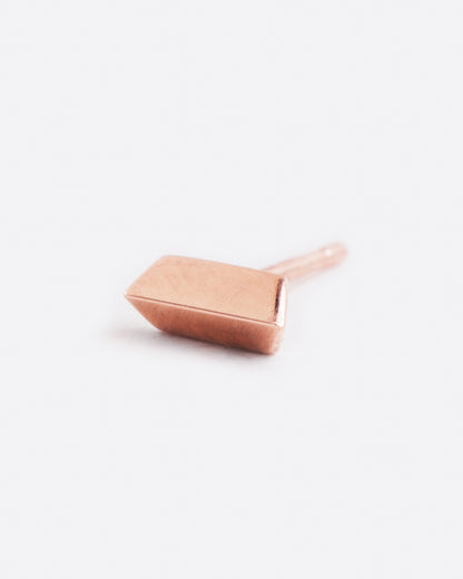 A rose gold stud earring with two angled sides. Shown lying flat from the side.