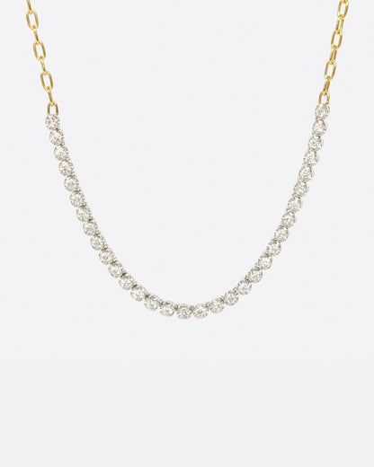 A yellow gold, oval link chain necklace with four inches of contrasting white diamonds, shown from the front.