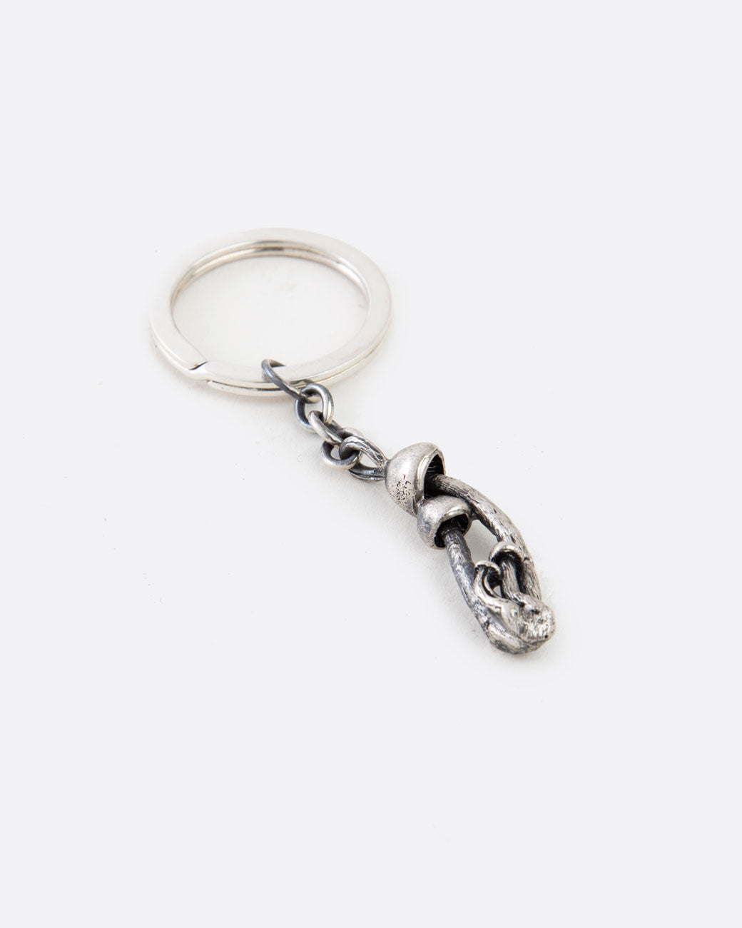 A silver keychain with a cluster of mushrooms. Shown lying flat at an angle from the front.