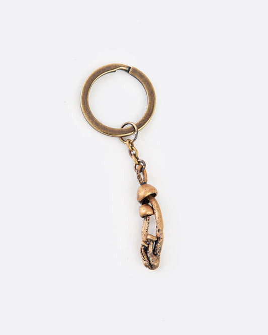 A bronze  keychain with a cluster of mushrooms. Shown lying flat from the front.