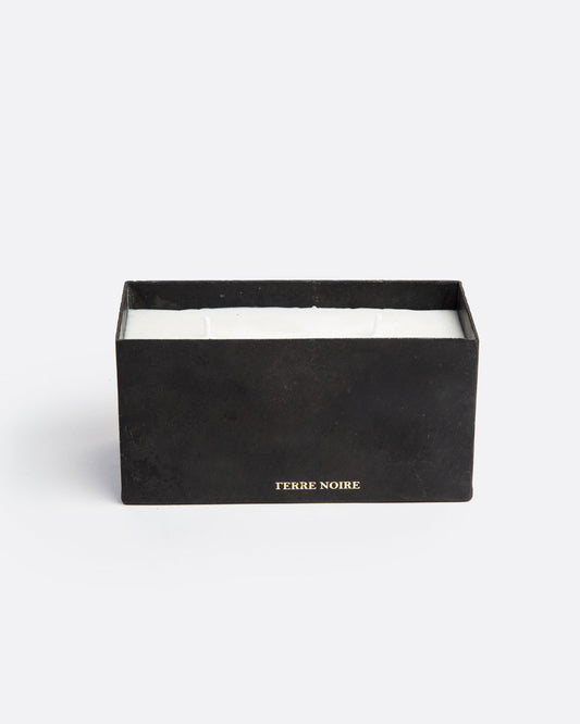 A white block candle with two wicks in a rectangular black container with TERRE NOIRE in gold lettering at the base. Shown from the front.