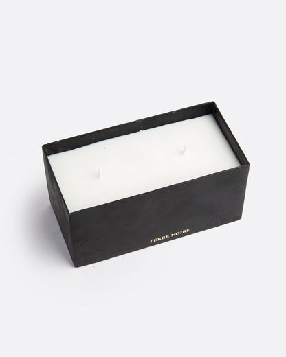 A white block candle with two wicks in a rectangular black container with TERRE NOIRE in gold lettering at the base. Shown from the top.