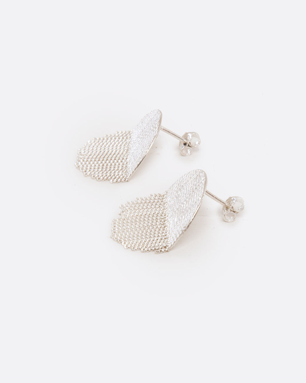 A pair of silver earrings with soldered half circle tops and chain fringe half circle bottoms. Shown lying flat from the side. With post backs and butterfly backings.