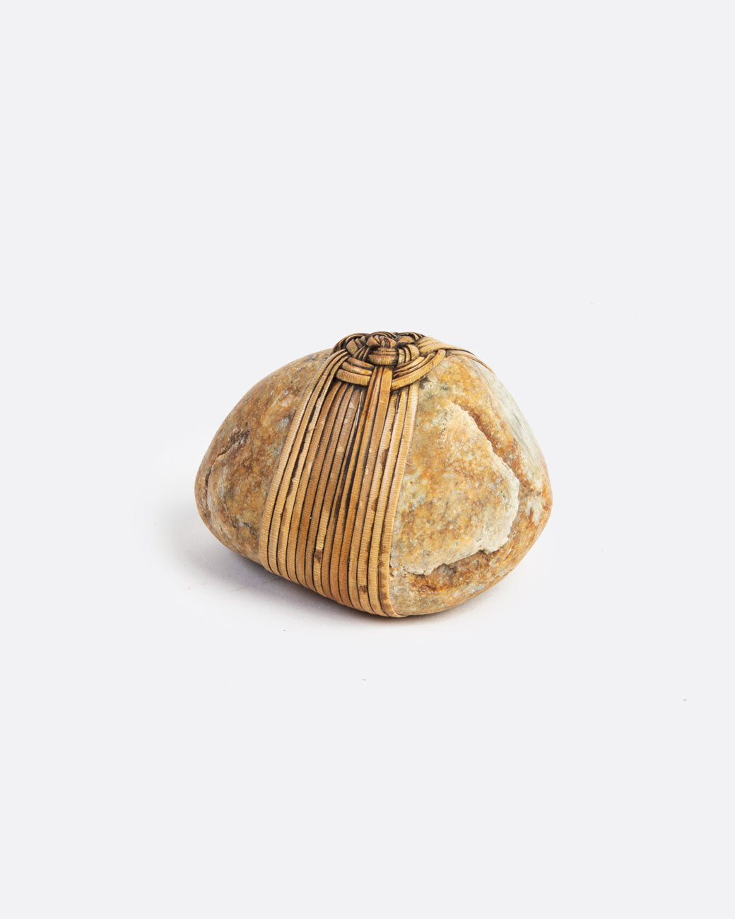 A blessing stone, wrapped in woven grass. Shown from the side.