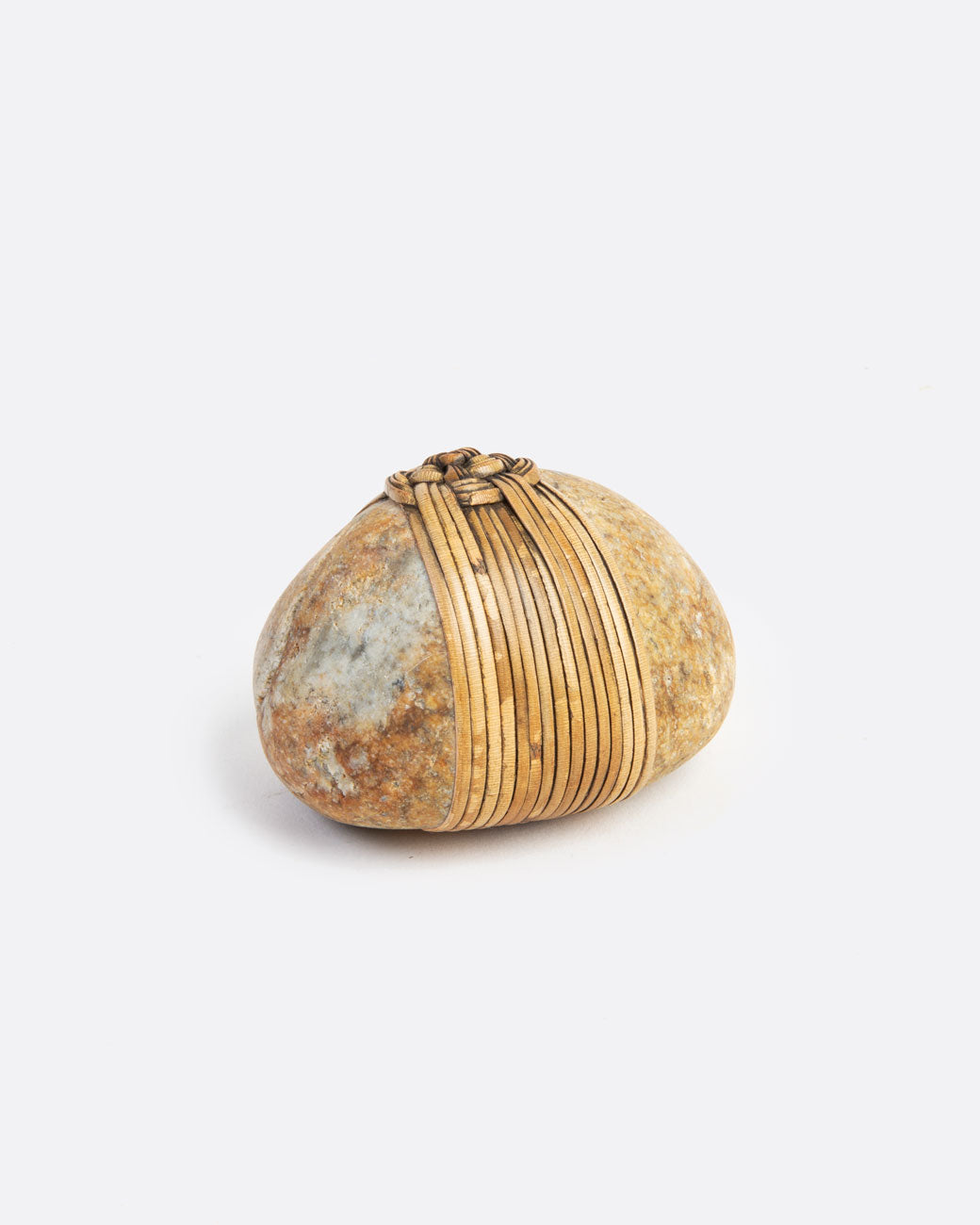 A blessing stone, wrapped in woven grass. Shown from the side.