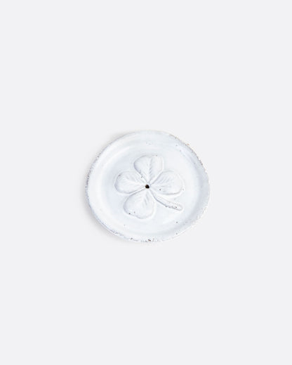 A round white incense burner with a four leaf clover pattern at the center and a whole in the center. Shown from the top.