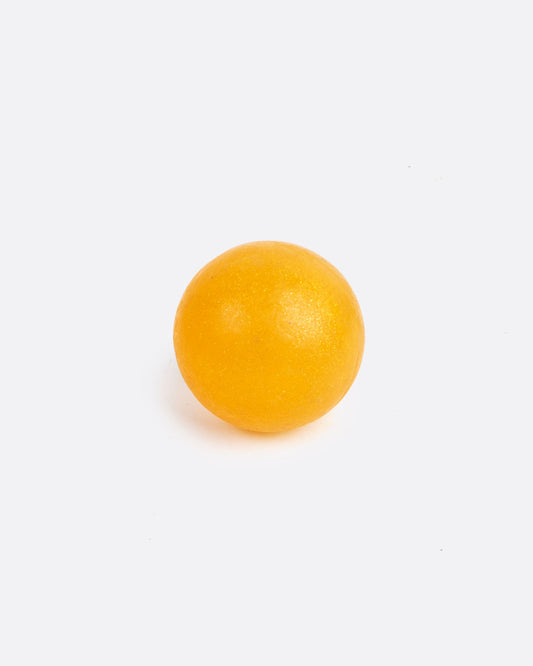 A golden- orange colored round sphere soap. Shown from the front.