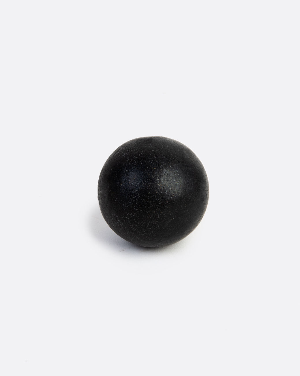 A sphere shaped black soap. Shown from the front.