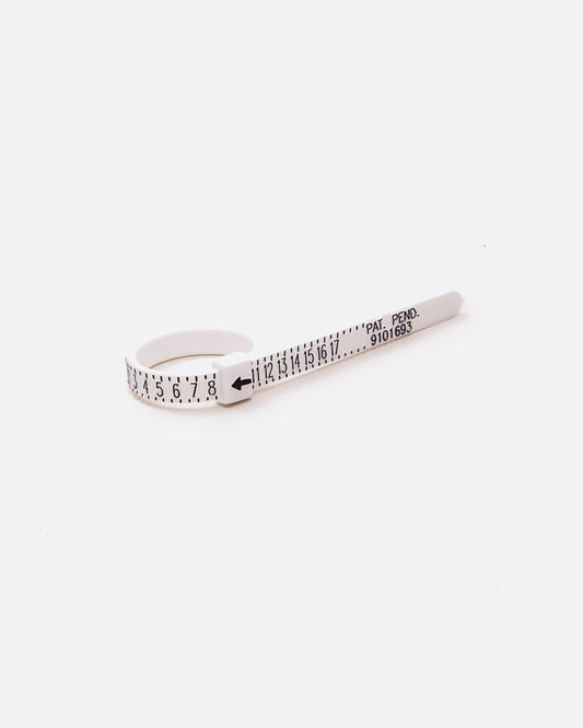 A white ring sizer with black numbering shown on its side from an angle. 