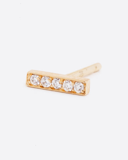 A yellow gold bar stud earring with five white diamonds. Shown lying on its side from the front.
