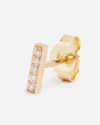A yellow gold bar stud earring with five white diamonds. Shown standing up from the front.