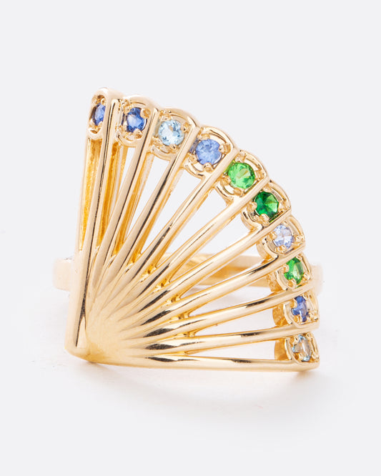 A yellow gold ring in the shape of a fan with multicolor sapphires along the top edge. Shown from the front. 