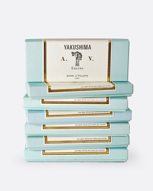 A stack of seven turquoise and white incense boxes with gold details.The top box is shown standing up from the front on top of the stack. The label reads: 'YAKUSHIMA A.V. Encens ASTIER de VILLATTE PARIS' with the image of a tree at the center.