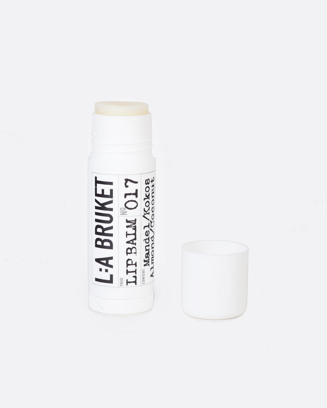 A 17 mL tube of L:A Bruket Almond & Coconut Lip Balm uncapped to show the clear white balm.
